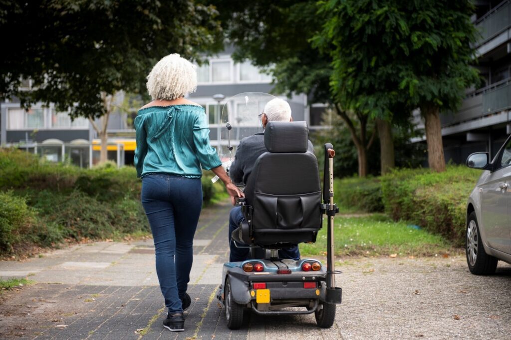 A Woman Walking and Man in Mobility Scooter | Buying Handicapped Accessible Products