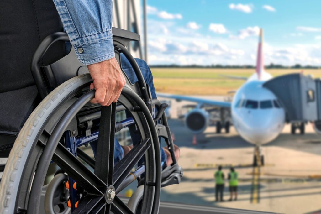 A wheelchair user looks out a window at an airplane, emphasizing the importance of mobility aids for travel.