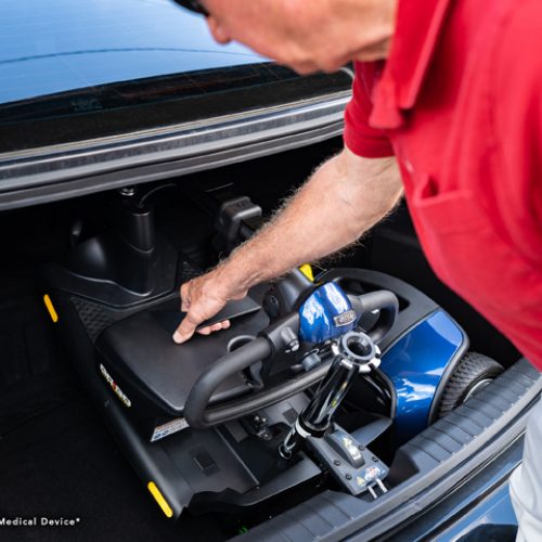 Man in Red Putting Folded Scooter in the Trunk | Mobility Service Provider